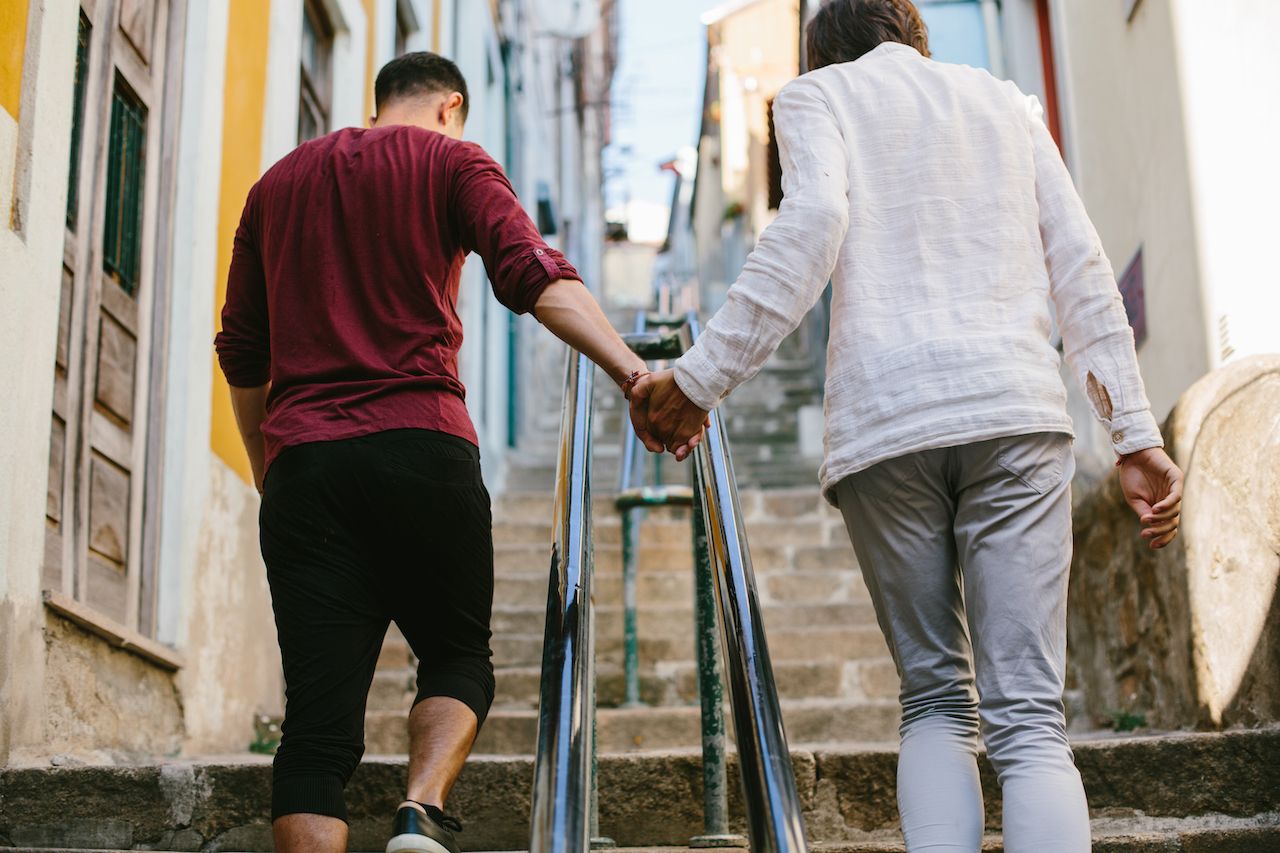 A gay couple traveling and walking outdoor on european city streets, keeping hands together