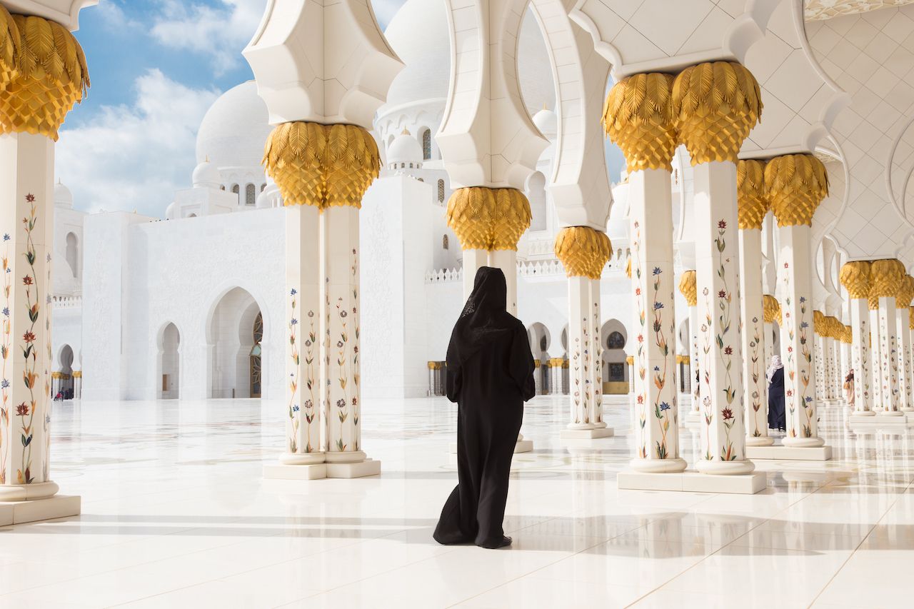 Traditionally dressed arabic woman wearing black burka wisiting Sheikh Zayed Grand Mosque in Abu Dhabi, United Arab Emirates